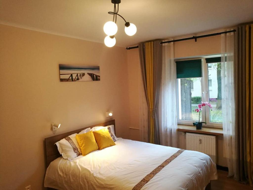 sypialnia z łóżkiem z żółtymi poduszkami i oknem w obiekcie Travel Apartment w Warszawie