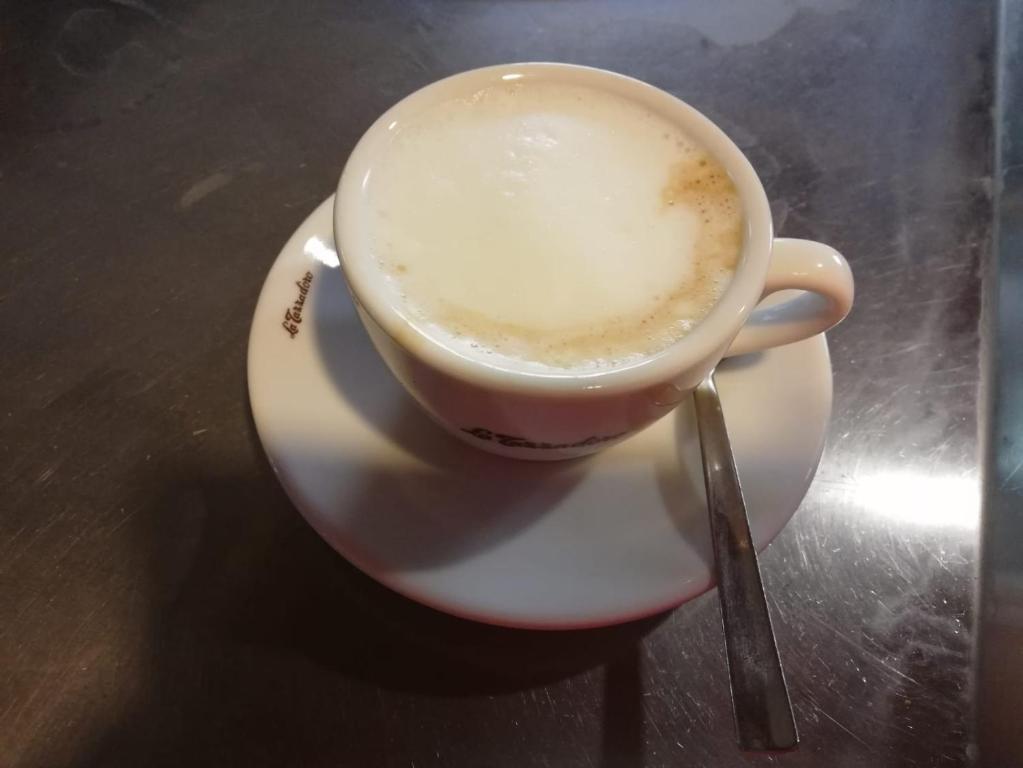 una taza de café sentada en un plato sobre una mesa en Hotel Sagittario, en San Sperate