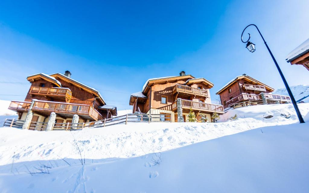 um grupo de casas de madeira na neve em Parc Madeleine - CHALETS em Saint-François-Longchamp