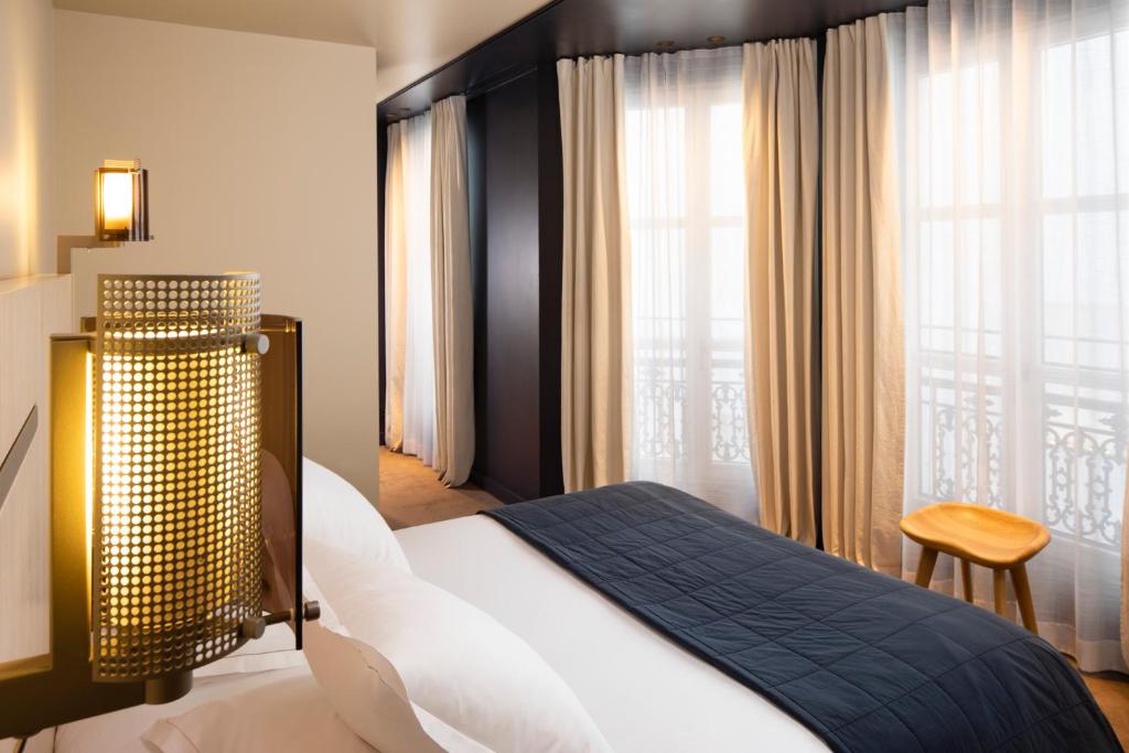 een slaapkamer met een bed en een groot raam bij Hotel de Nell in Parijs