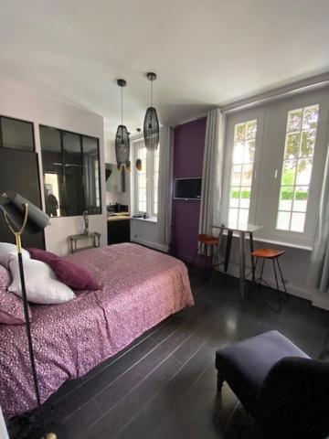 um quarto com uma cama com lençóis roxos e janelas em KRISKO em Armentières