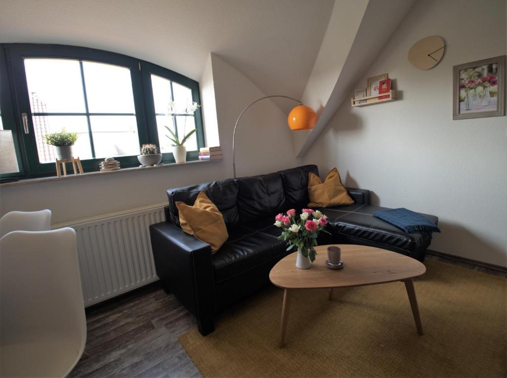 a living room with a black leather couch and a table at de lütte Kabuff in Born