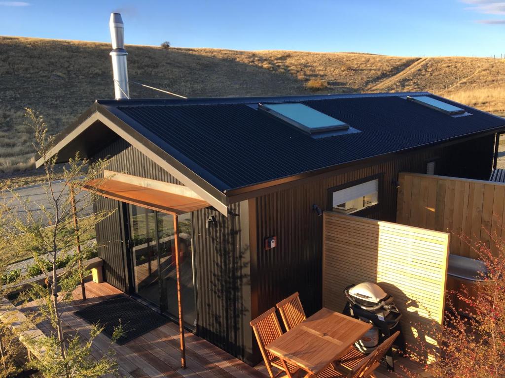 a small house with a solar roof on a deck at Skylight House with Stunning Outdoor Bath in Lake Tekapo