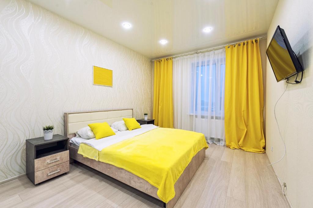 a bedroom with a bed with yellow sheets and a tv at SC Apart Ostrovskogo 93Б in Perm in Perm