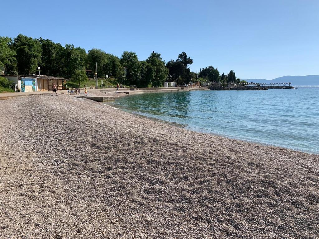 - une plage avec une personne qui se promène au bord de l'eau dans l'établissement Apartman Polje, à Njivice