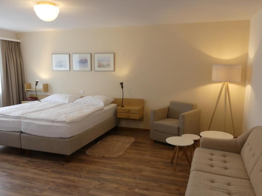 ein Schlafzimmer mit einem Bett, einem Sofa und einem Stuhl in der Unterkunft Hotel Adler in Stein am Rhein