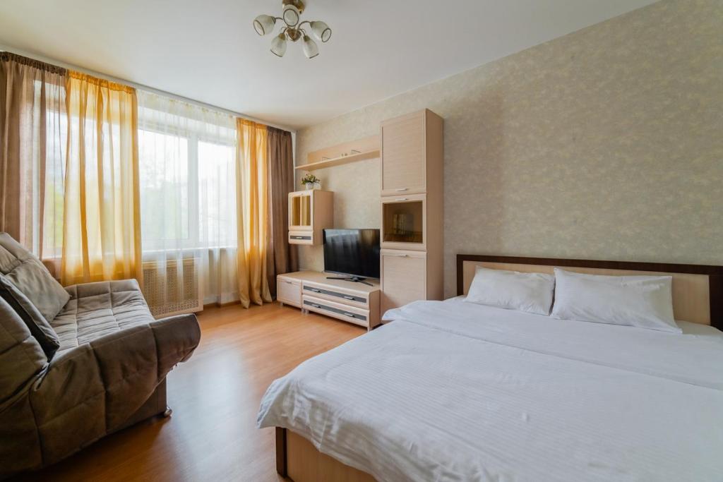 1 dormitorio con cama, sofá y TV en Apartments on Ploscha Yakuba Kolasa en Minsk
