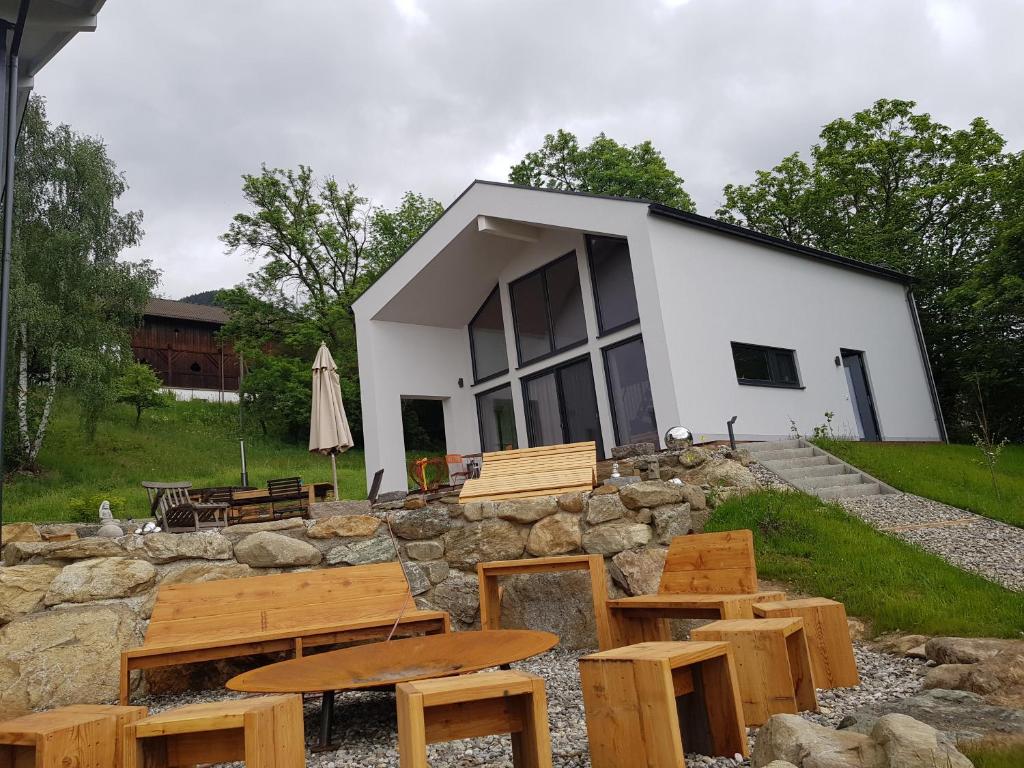 un bâtiment avec des tables et des chaises en bois devant lui dans l'établissement Casa Joia Rara, à Millstatt