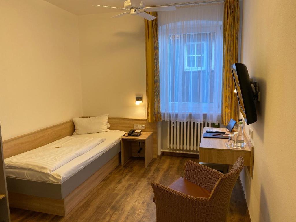 a small room with a bed and a desk and a television at Hotel Gasthof Zum Storch in Schlüsselfeld