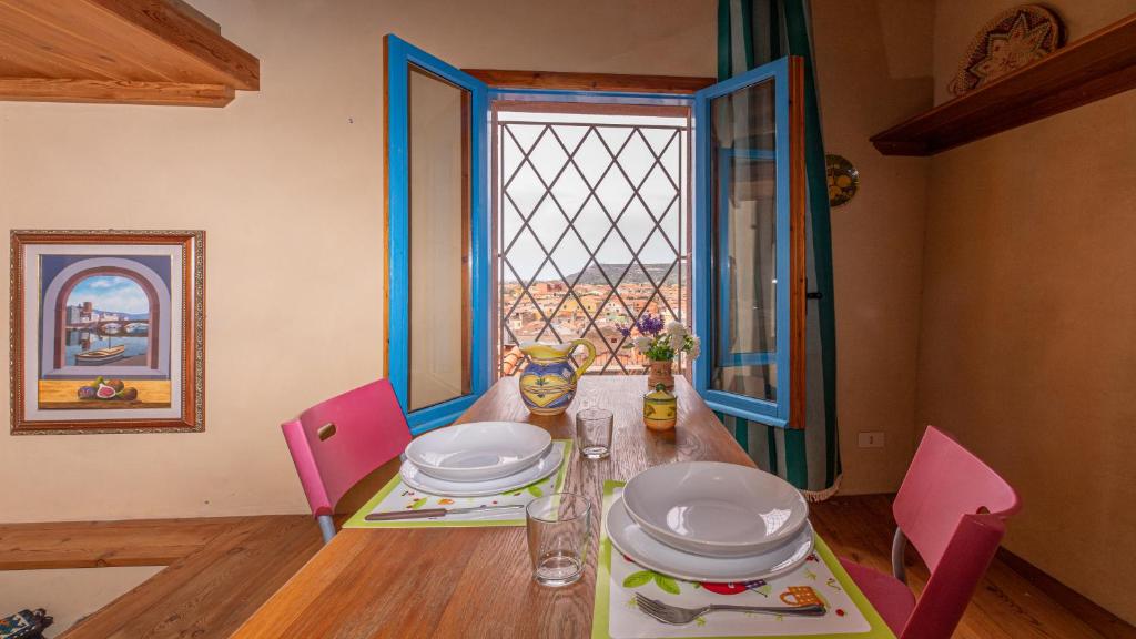 a dining room table with pink chairs and a window at Welcomely - Casa Portella in Bosa