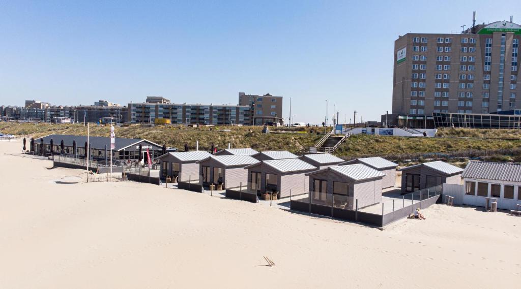 rząd domków plażowych na piaszczystej plaży w obiekcie STRAND 21 hotelchalets w Zandvoort