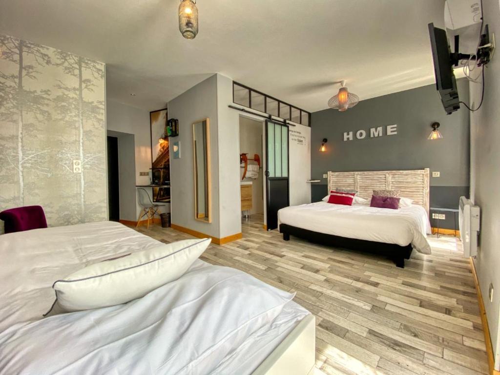 a bedroom with two beds and a home sign on the wall at Hôtel Le P'tit Monde in Montignac