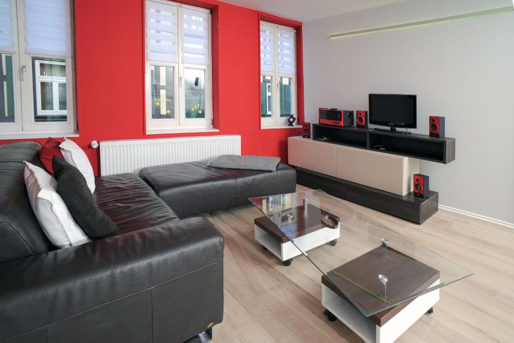 een woonkamer met een zwarte bank en een rode muur bij Design-Ferienwohnungen Stadtidyll in Wernigerode