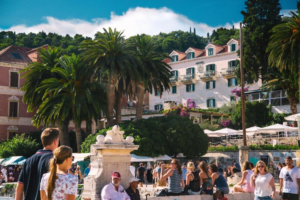 um grupo de pessoas andando em torno de uma fonte em frente a um edifício em Heritage Hotel Park Hvar em Hvar