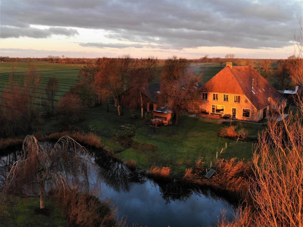 una casa sentada en la cima de un campo junto a un río en Vakantiehuis met hottub De Opkikker, en Giethoorn