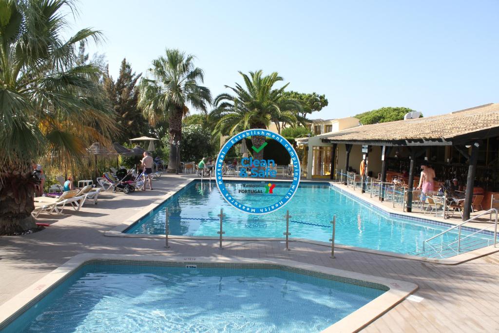 a swimming pool with a blue circle in the middle at Hotel Pinhal do Sol in Quarteira