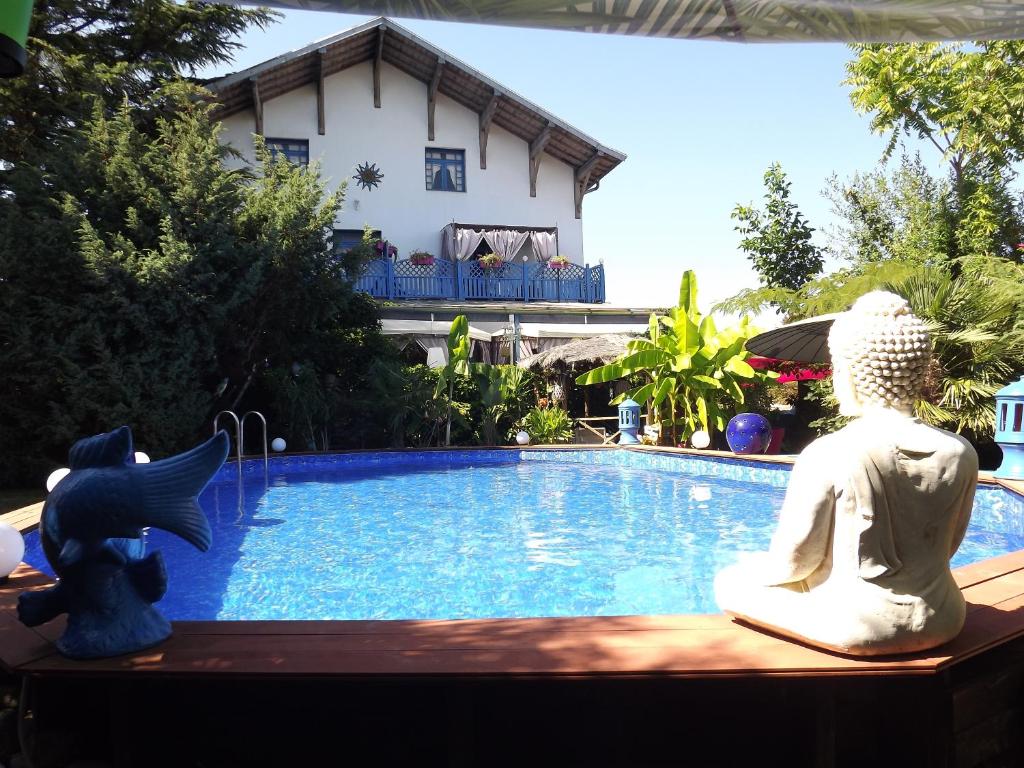 une piscine avec deux statues assises à côté d'une maison dans l'établissement Chambres d'hotes La Maison Bleue, à Souvans