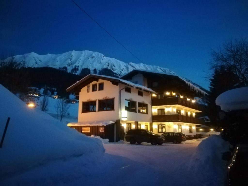 ein Gebäude im Schnee bei Nacht mit Bergen in der Unterkunft Bed & Breakfast Der Tiroler in Achenkirch