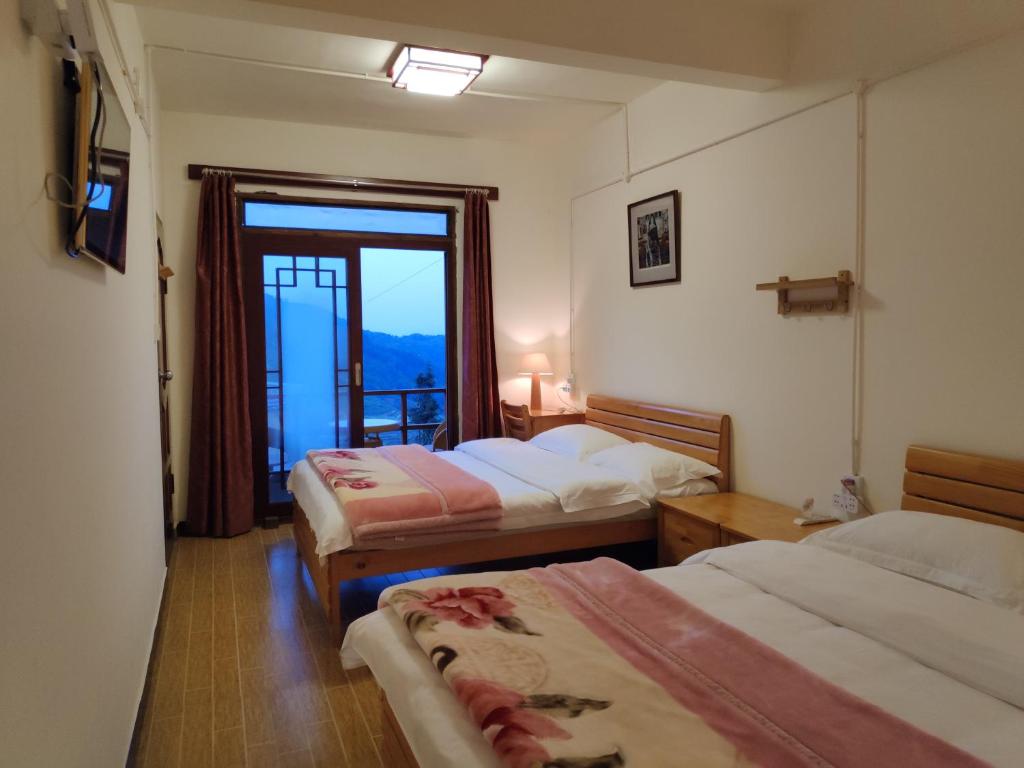 ein Hotelzimmer mit 2 Betten und einem Fenster in der Unterkunft 多依湾客栈Havre de paix DuoYiWan in Kreis Yuanyang