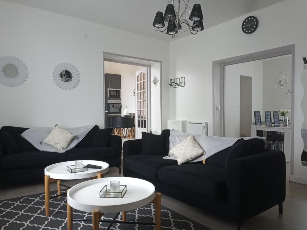 a living room with two black couches and two tables at duplex agréable et calme in Château-Thierry