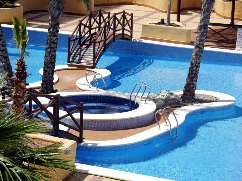 a swimming pool with two chairs in a pool with palm trees at Verdemar 3 - 1306 in Playa Honda