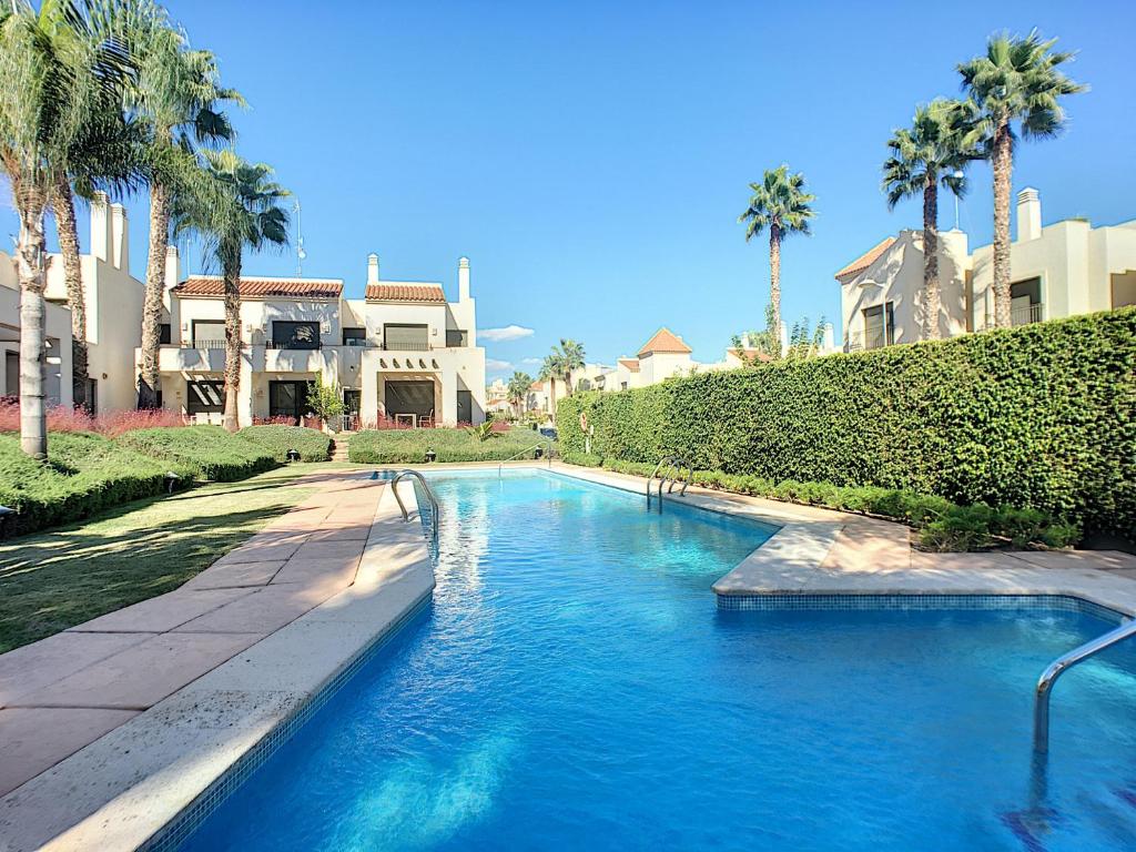 - une piscine en face d'une maison avec des palmiers dans l'établissement Roda Golf Resort 4109 - Nicky, à San Javier