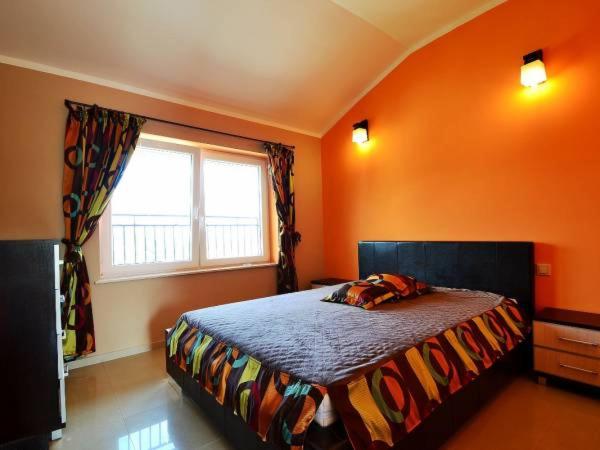 a bedroom with orange walls and a bed with a window at Willa Galeon in Sarbinowo