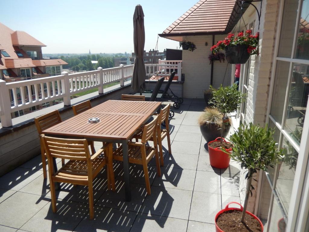 a deck with a wooden table and chairs on a balcony at ROYAL GARDENS DAKTERRAS in Blankenberge