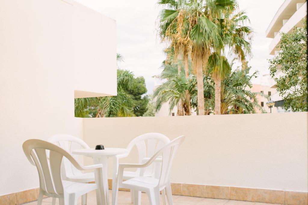 une table et des chaises blanches ainsi que des palmiers dans l'établissement Festival Village Apartments, à Salou