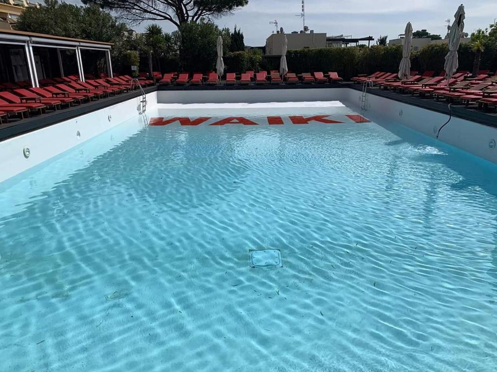 uma grande piscina com água azul e cadeiras vermelhas em Studio Naturiste "LIBERTY" Héliopolis K 125 em Cap d'Agde