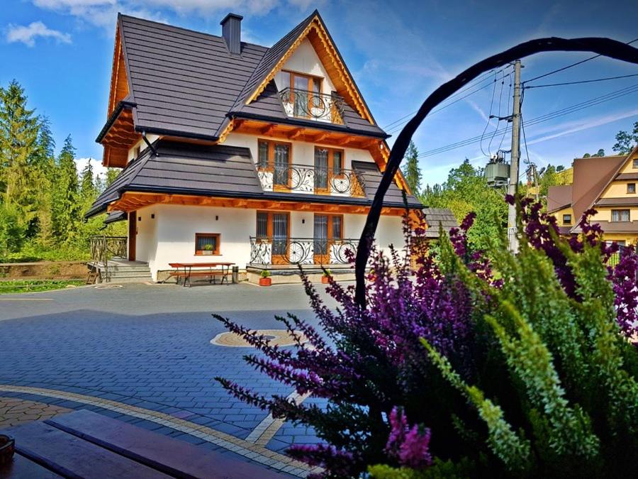 una casa con flores púrpuras delante de ella en Willa Pasternik, en Małe Ciche