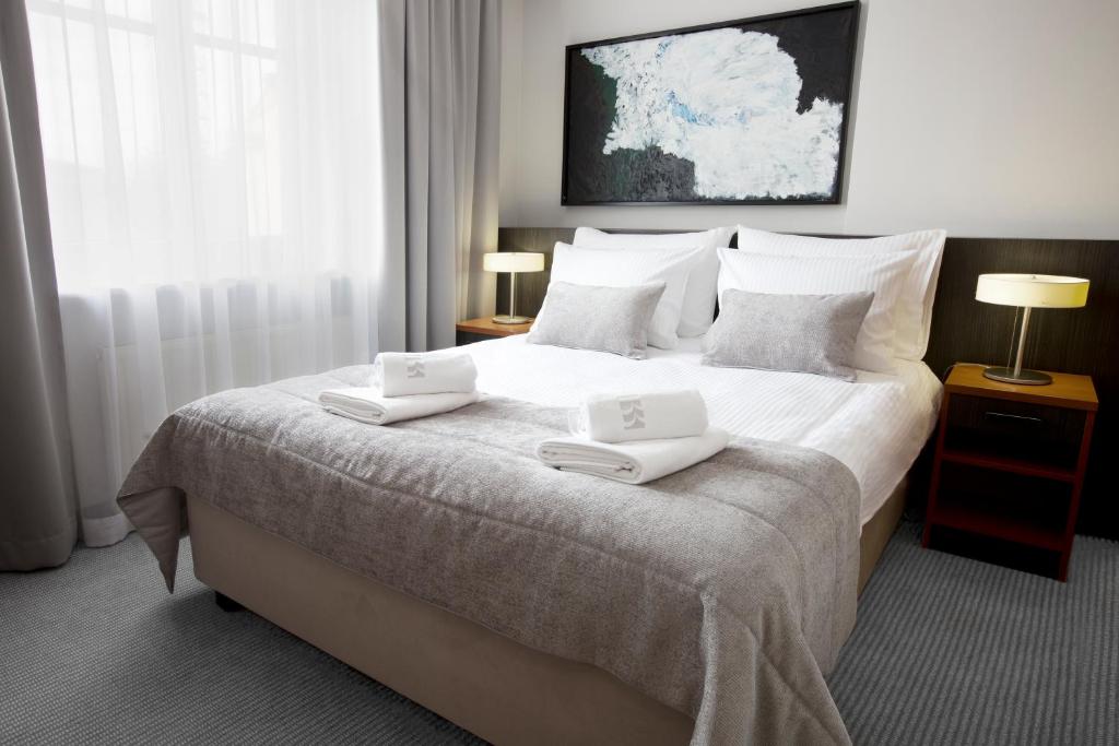 a bedroom with a large bed with two white towels on it at Benefis Boutique Hotel in Krakow