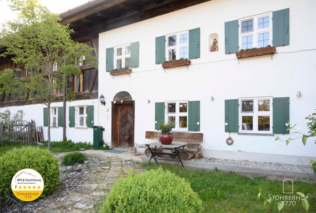 une maison blanche avec des volets verts et une porte dans l'établissement 5 Sterne Ferienhaus Gut Stohrerhof am Ammersee in Bayern bis 11 Personen, à Dießen am Ammersee