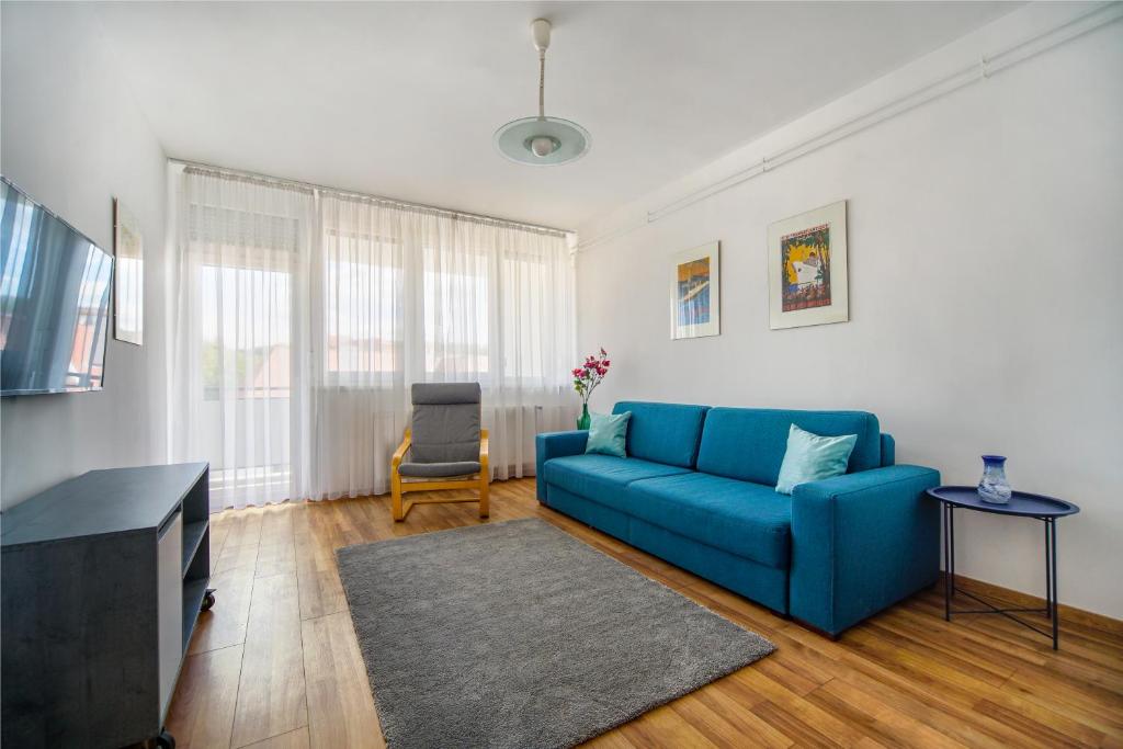 a living room with a blue couch and a tv at Illy Apartman in Eger
