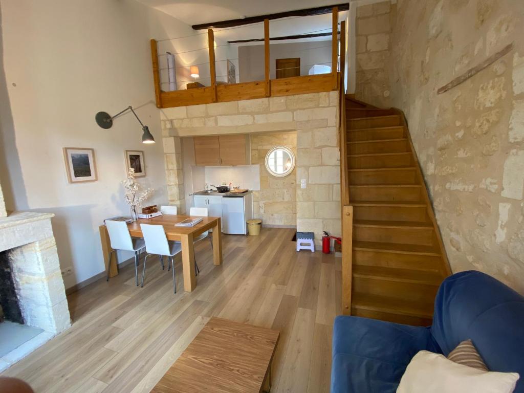 a living room and dining room with a staircase and a table at Appartement Saint Emilion in Saint-Émilion