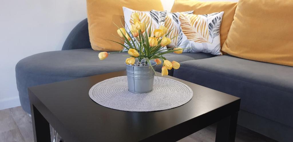 um vaso de tulipas amarelas numa mesa em frente a um sofá em Apartament SŁONECZNY Pięć mórz Sianożęty em Poland