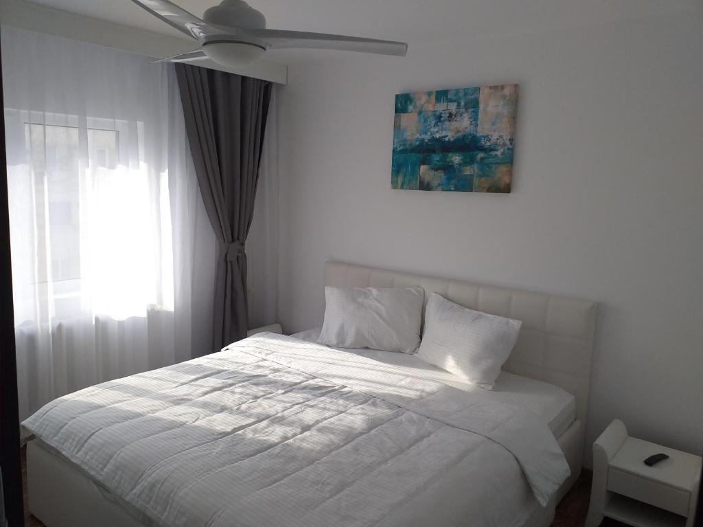 a bedroom with a white bed with a ceiling fan at Seaside Home Apartment in Mangalia