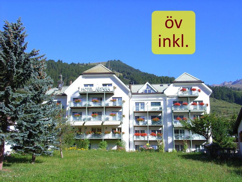 un gran edificio de apartamentos en una colina con un cartel en Typically Swiss Hotel Altana, en Scuol