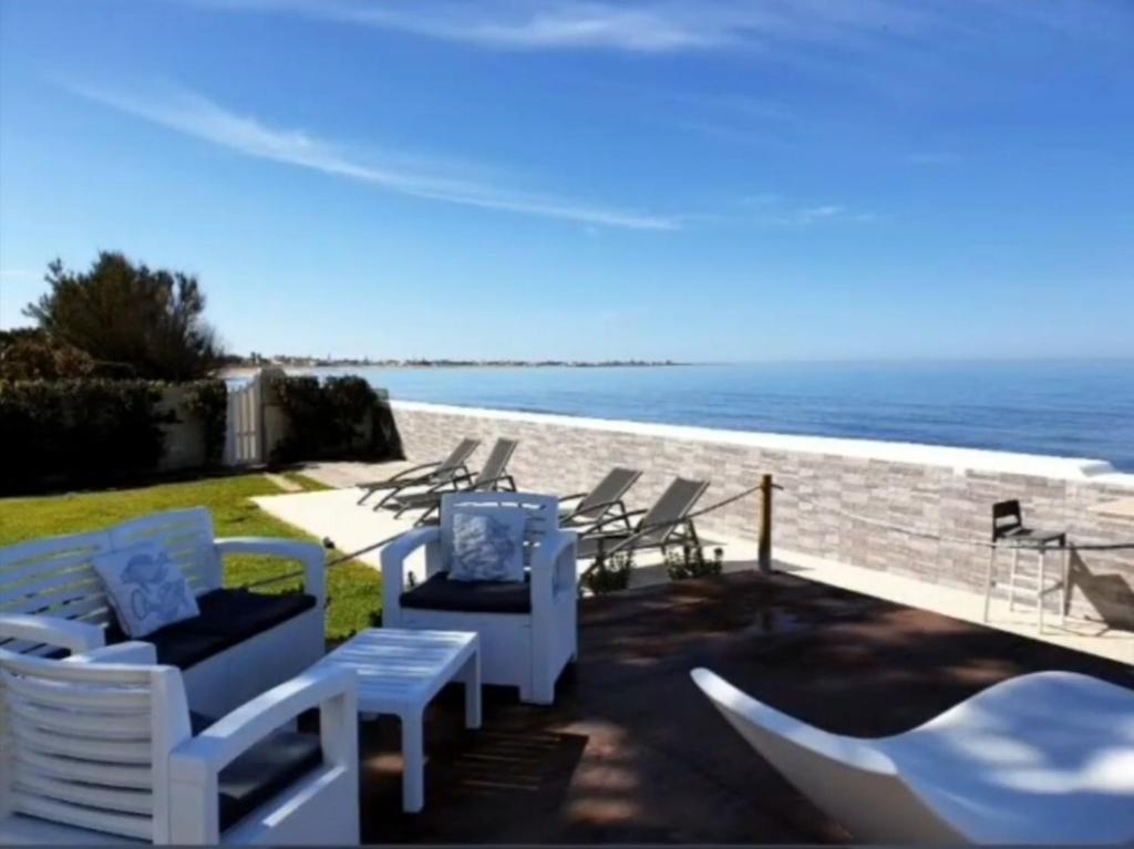 un grupo de sillas y mesas en un patio con vistas al océano en SUITEBEACH b&b and resort, en Marsala