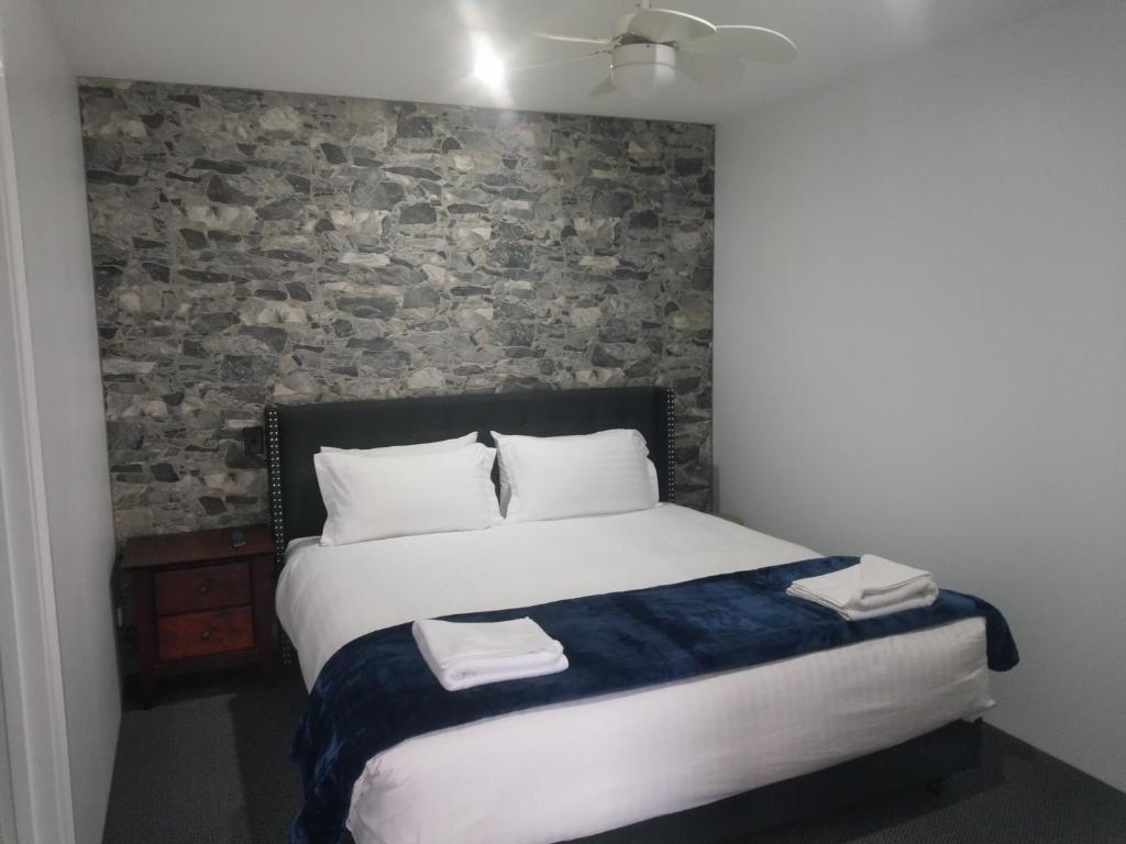 een bed in een kamer met een bakstenen muur bij Happy Wanderer Motel Bendigo CHILDREN NOT PERMITTED over 18s only in Bendigo