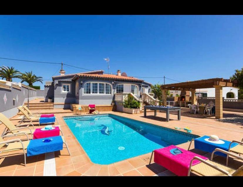 a swimming pool with chairs and a house at Villa Ingrid in Alaior