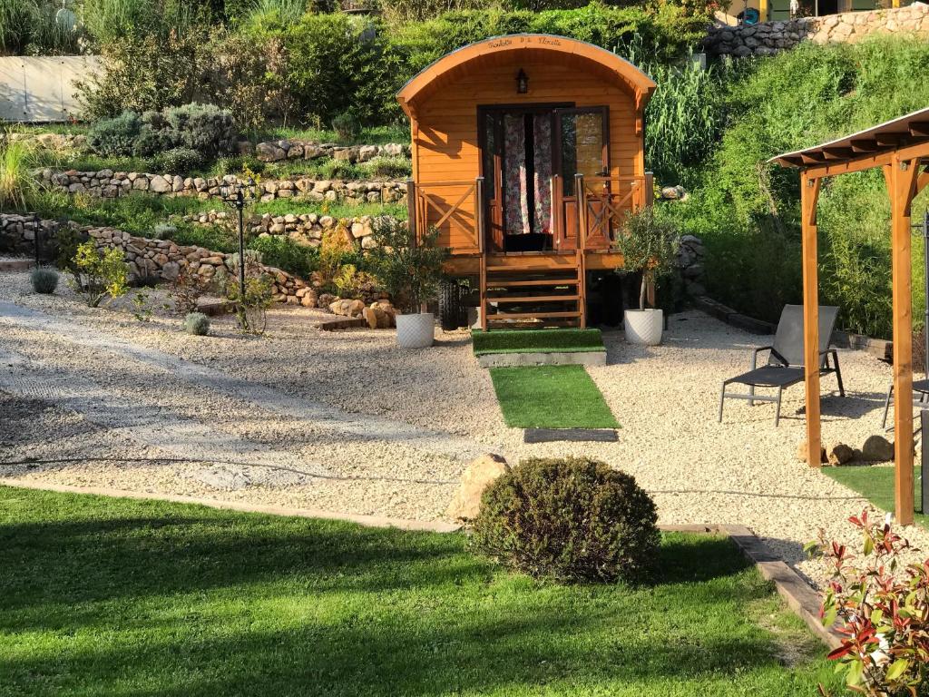 eine kleine Holzhütte in einem Garten mit Gras in der Unterkunft Roulotte de Florette in Tourrettes-sur-Loup