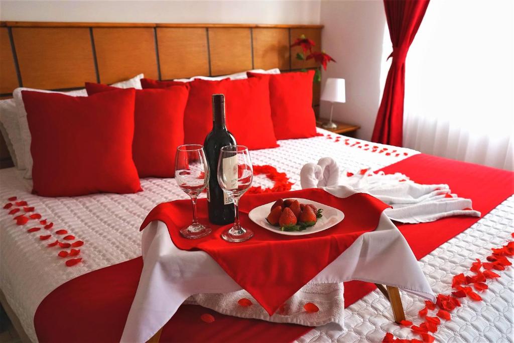 a red and white bed with a plate of fruit and wine glasses at Hotel Embajada Real in Bogotá