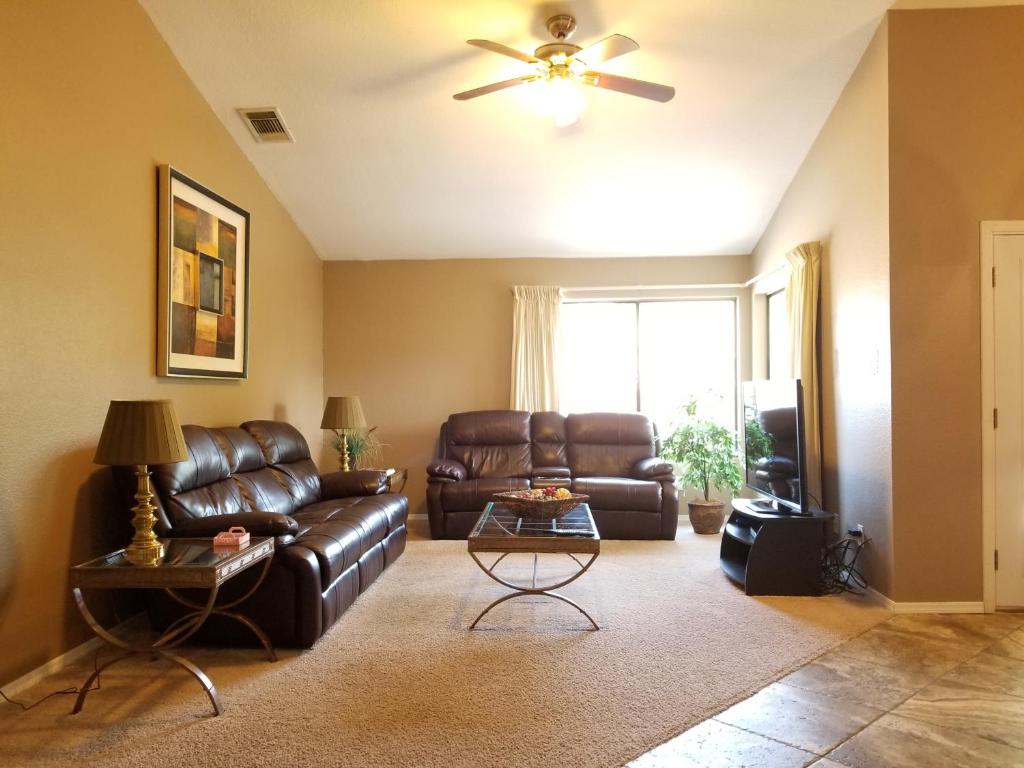 sala de estar con sofá de cuero y ventilador de techo en Quiet Neighborhood off La Canada, en Tucson