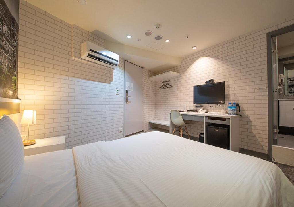a bedroom with a bed and a desk with a television at 9ine Hotel in Taipei
