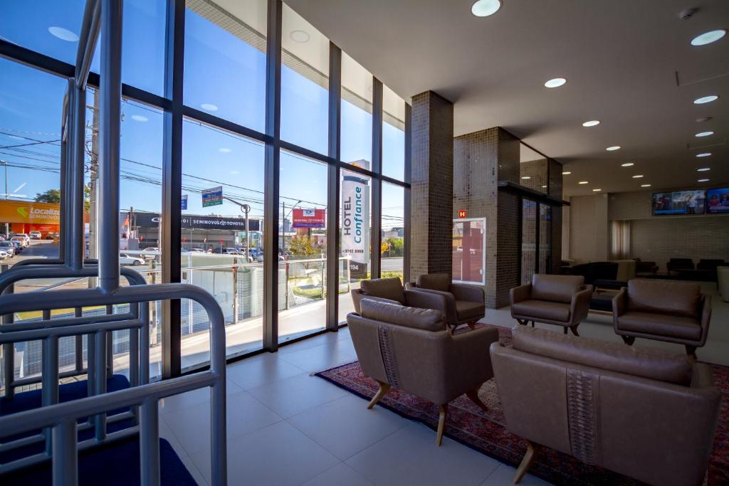 poczekalnia z krzesłami i oknami w budynku w obiekcie Hotel Confiance Barigui w mieście Kurytyba