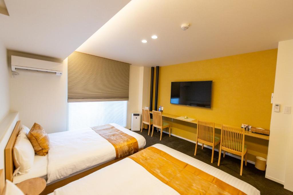 a hotel room with two beds and a desk at GRAND BASE Hiroshima Ekimae in Hiroshima