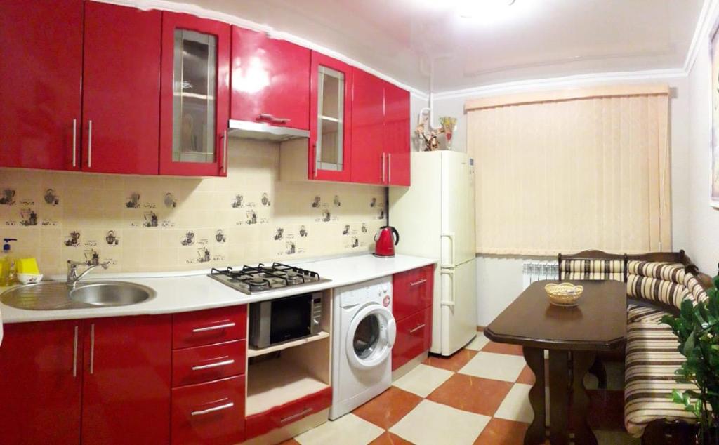 a kitchen with red cabinets and a sink and a microwave at Apartment Eva in Stavropol