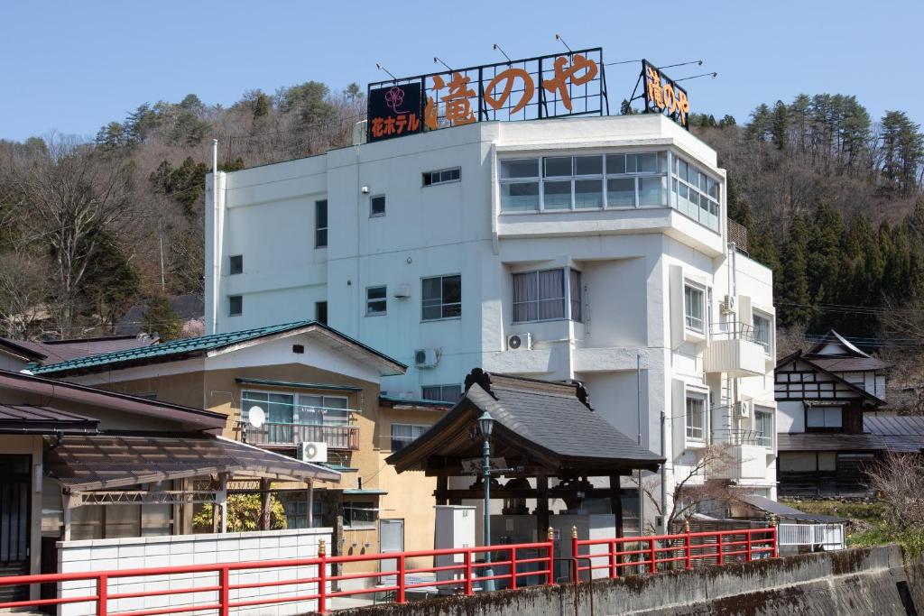 a white building with a sign on top of it at Tabist Hana Hotel Takinoya Aizu-Yanaizu in Yanaizu
