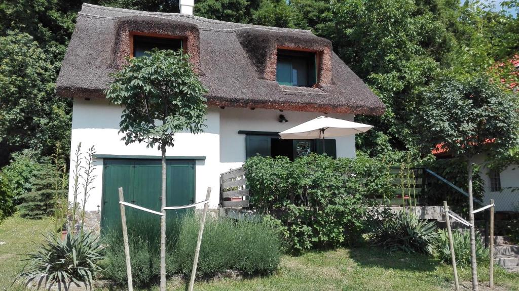 une maison avec un toit de chaume et une porte verte dans l'établissement Peace & Beach House in Tihany, Sajkod, à Tihany